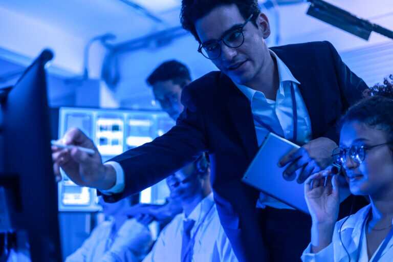 Project Manager Pointing At Computer Screen To Explain And Help