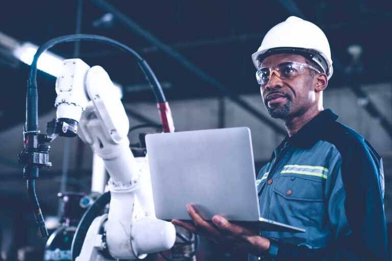 African American Factory Worker Working With Adept Robotic Arm