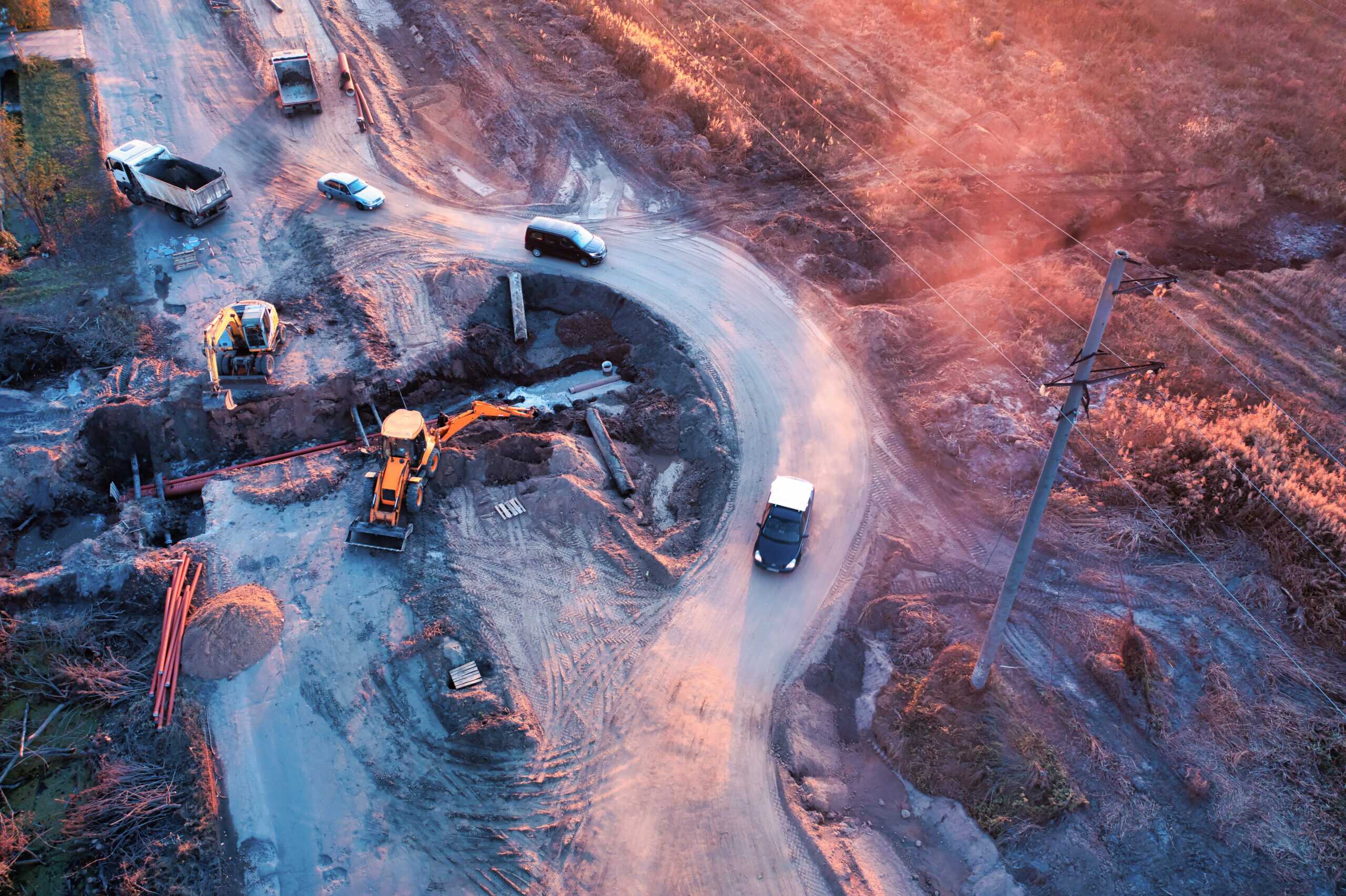 Aerial photograph showing a construction site with earthmoving machinery and vehicles on a curved dirt road.
