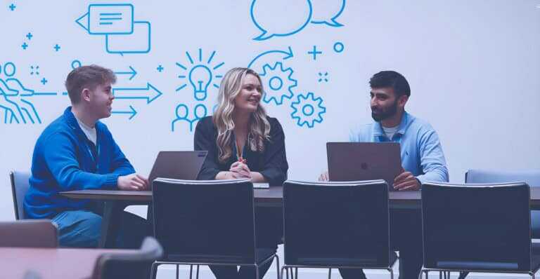 Three people in an office socialising together with laptops