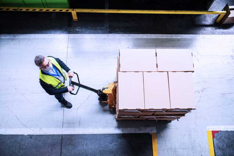 Aerial View Of Man Worker With Protective Mask Working In Industrial Factory Or Warehouse.
