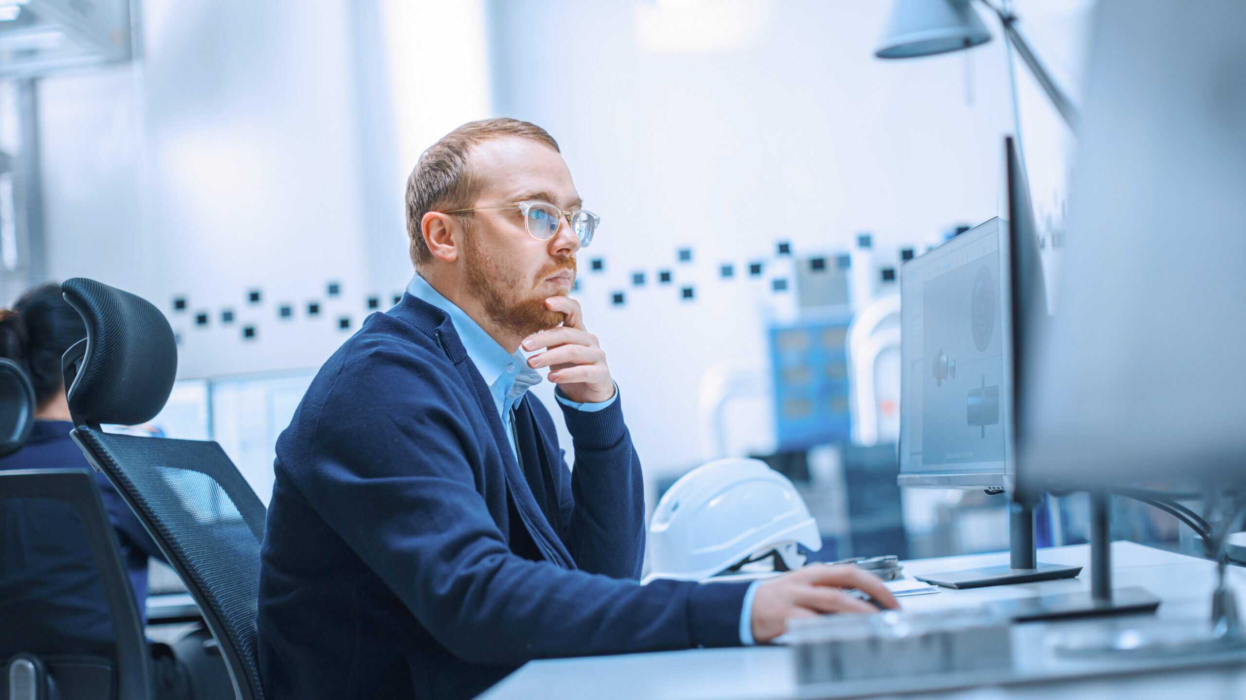Photograph showing a person sitting at a desk looking at a computer.