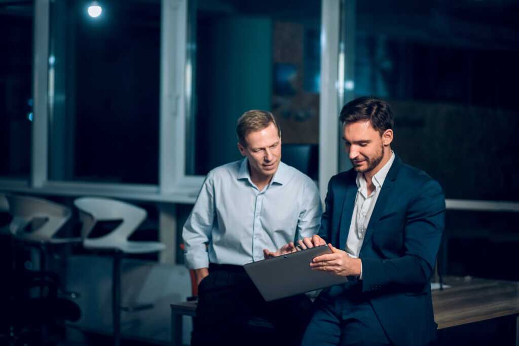 Two Busienessmen Working Late In Office.