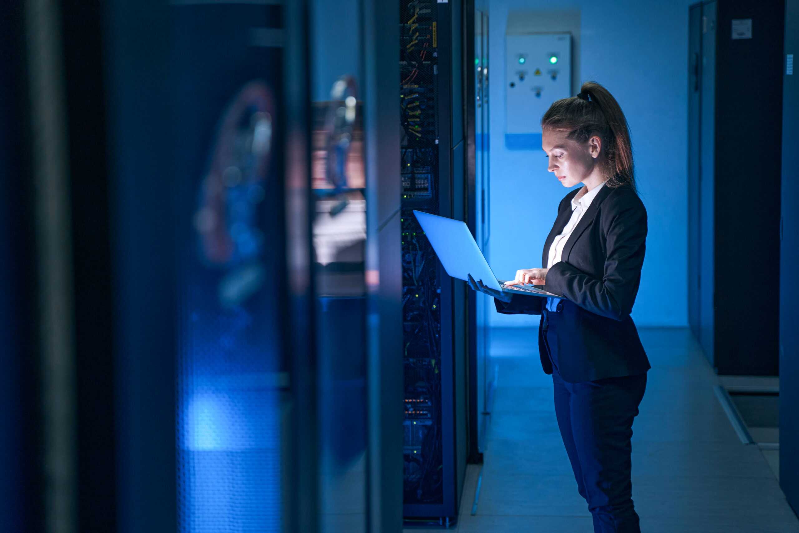 Female Engineer Working In Server Room At Modern Data Center