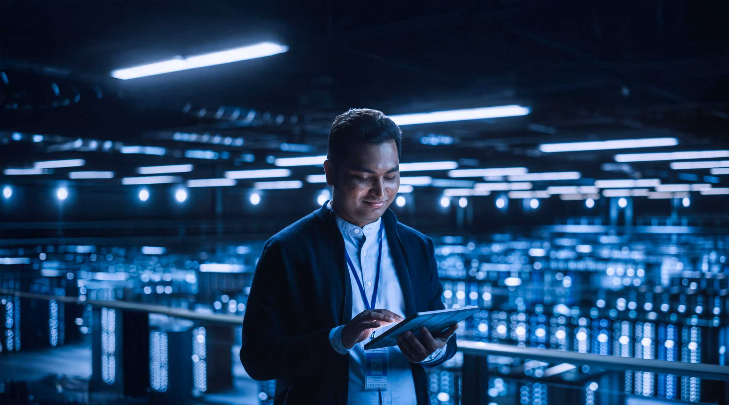 Handsome Smiling It Specialist Using Tablet Computer In Data Cen
