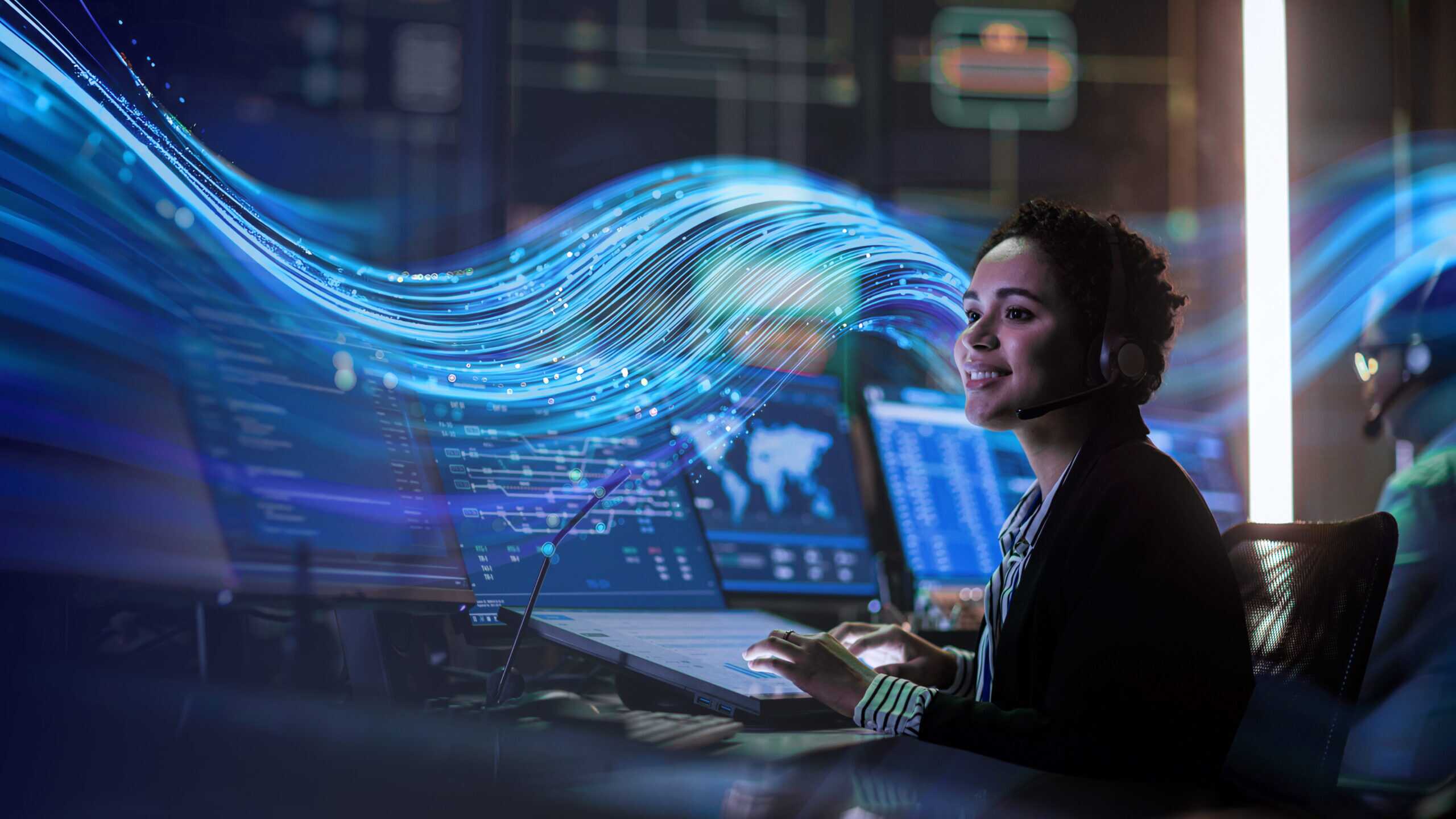 Woman working at a multi-monitor computer setup, with the SCC wave graphic in the background