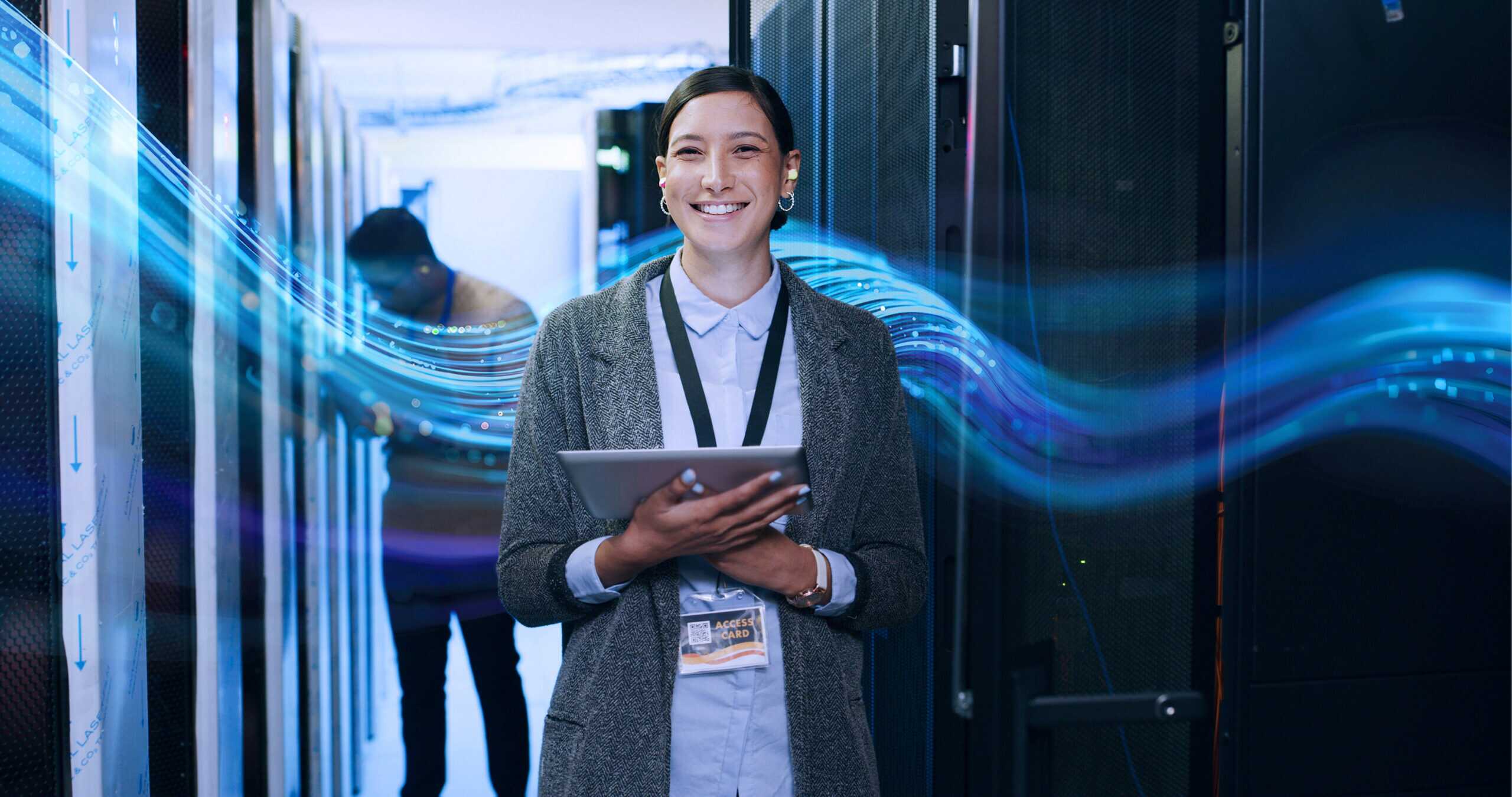 Two IT professionals working inside a server room with racks of servers on both sides, with the SCC wave graphic in the background.